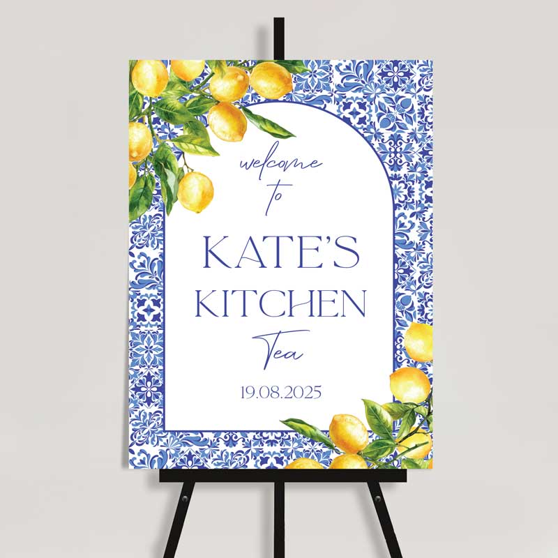 Welcome sign for Kate’s Kitchen Tea on an easel, featuring a blue Mediterranean tile pattern border, lemon illustrations, and elegant script and serif fonts. Date displayed as 19.08.2025.
